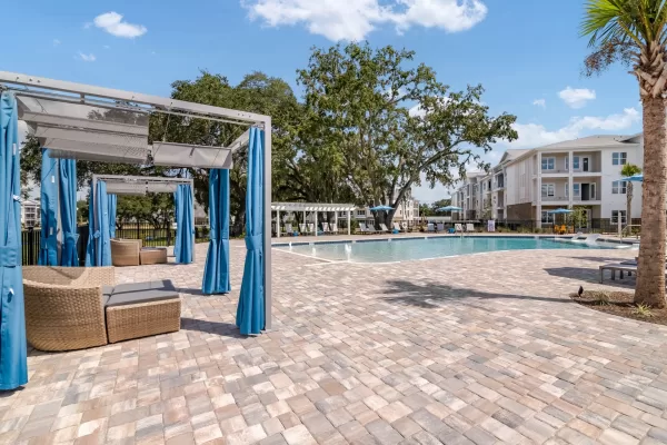Sparkling, blue pool and expansive sundeck with tanning ledge, poolside lounging, and private cabanas
