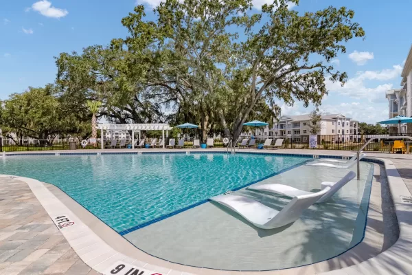 Sparkling, blue pool and expansive sundeck with tanning ledge and poolside lounging