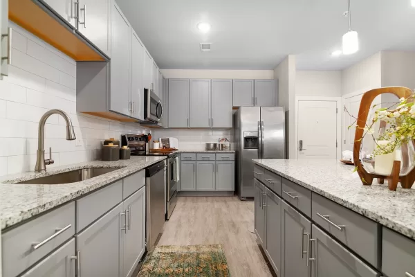 Gourmet kitchen with hardwood-style flooring, designer shaker-style cabinetry, kitchen island, granite countertops. and stainless steel appliances, including a side-by-side refrigerator, built-in microwave, stove, oven, dishwasher, and sink